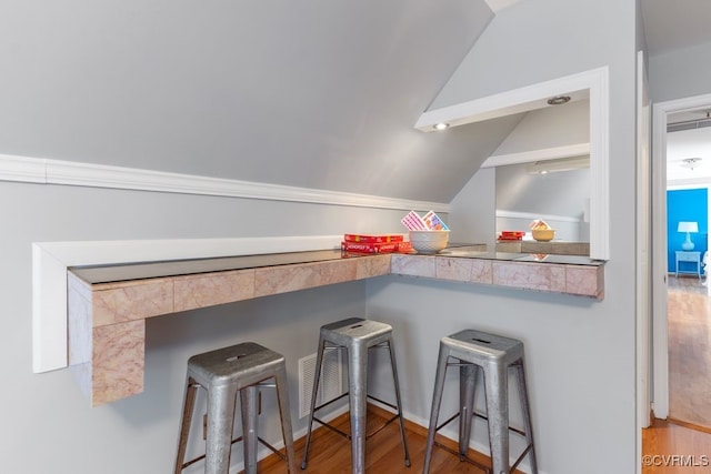 kitchen featuring lofted ceiling, hardwood / wood-style floors, and a breakfast bar