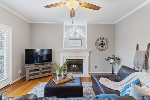 living room with ceiling fan, a premium fireplace, light wood-type flooring, and crown molding