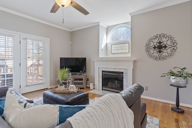 living room featuring light hardwood / wood-style floors, ceiling fan, ornamental molding, and a fireplace