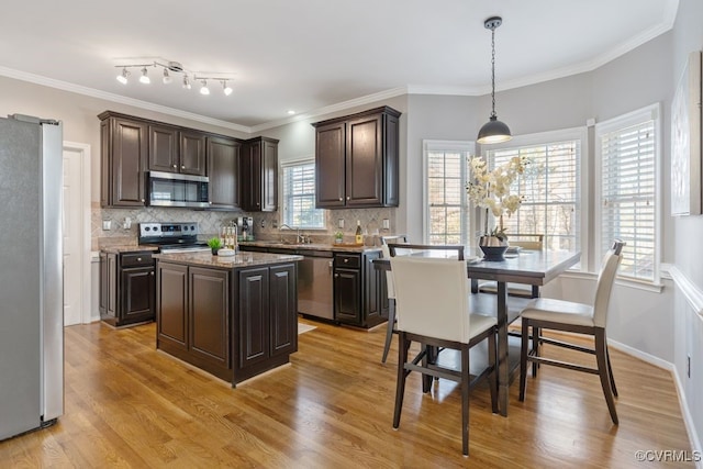 kitchen featuring appliances with stainless steel finishes, pendant lighting, decorative backsplash, and a kitchen island