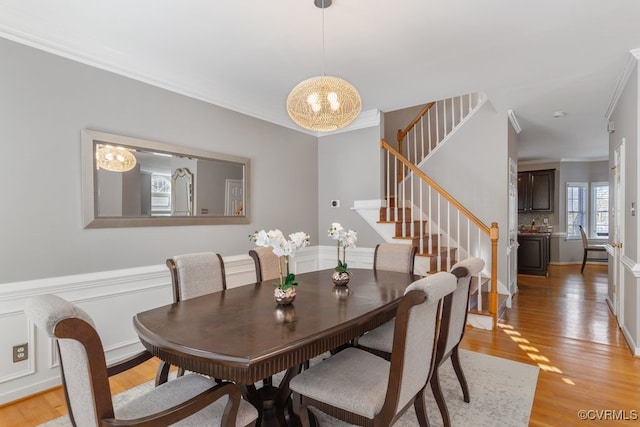 dining area featuring a notable chandelier, light wood-type flooring, and crown molding