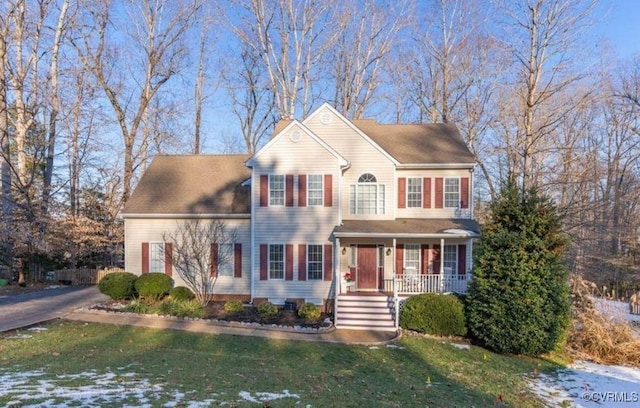 colonial house featuring a porch and a front lawn