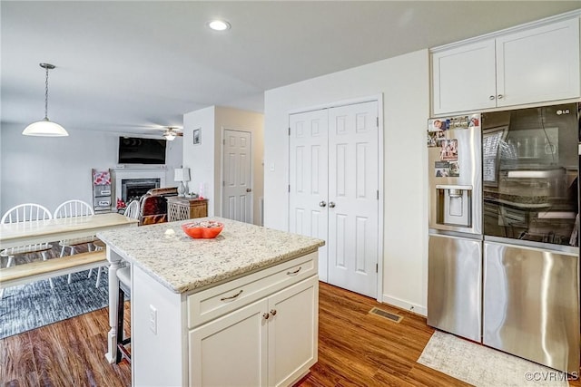 kitchen featuring a center island, hanging light fixtures, white cabinets, dark wood-type flooring, and stainless steel fridge