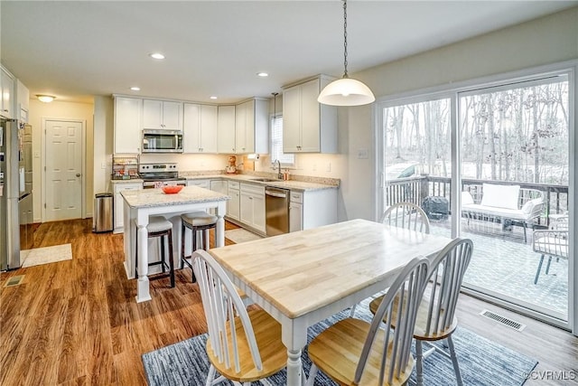 kitchen with sink, pendant lighting, white cabinets, and stainless steel appliances