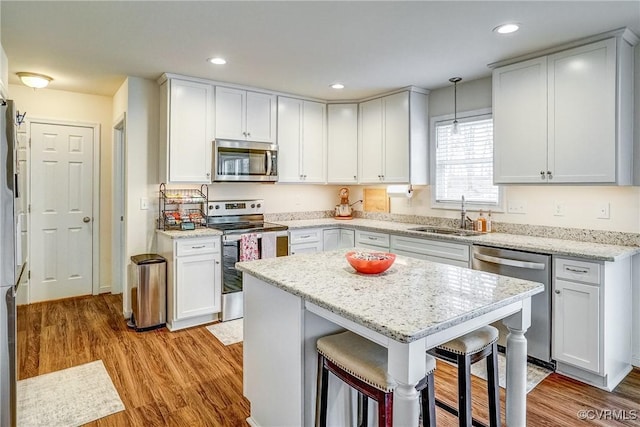 kitchen featuring sink, white cabinetry, appliances with stainless steel finishes, and pendant lighting