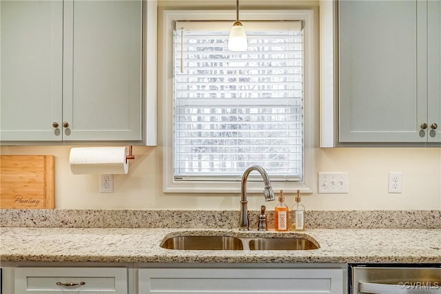 kitchen featuring sink, dishwasher, hanging light fixtures, and light stone countertops