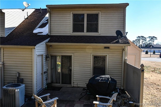 rear view of house with a patio, central AC unit, roof with shingles, and fence