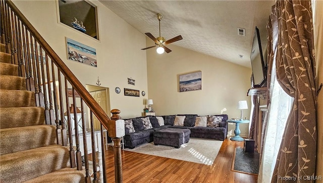 living room with hardwood / wood-style flooring, ceiling fan, high vaulted ceiling, and a textured ceiling