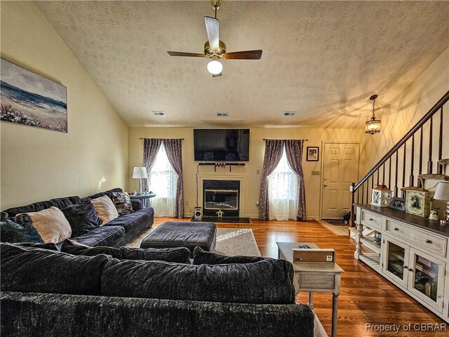 living room featuring ceiling fan, hardwood / wood-style floors, and a textured ceiling