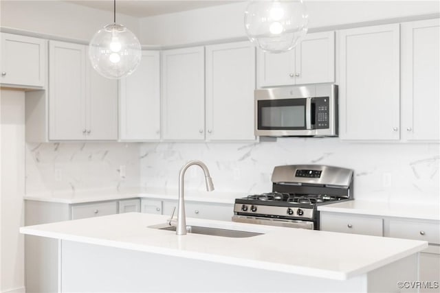 kitchen featuring stainless steel appliances, sink, decorative light fixtures, white cabinetry, and backsplash