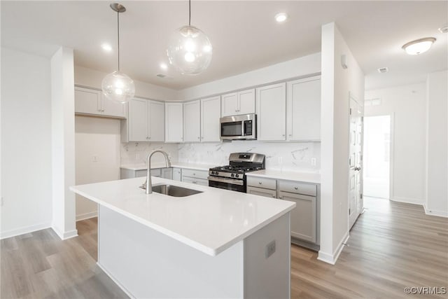 kitchen with stainless steel appliances, a center island with sink, pendant lighting, and sink