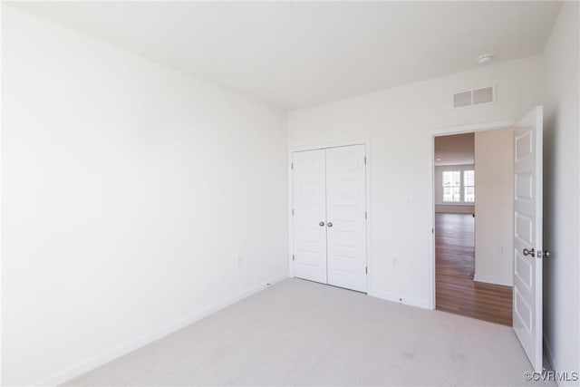 unfurnished bedroom with a closet and light carpet