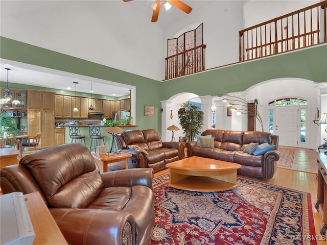 living room with a high ceiling, decorative columns, and ceiling fan