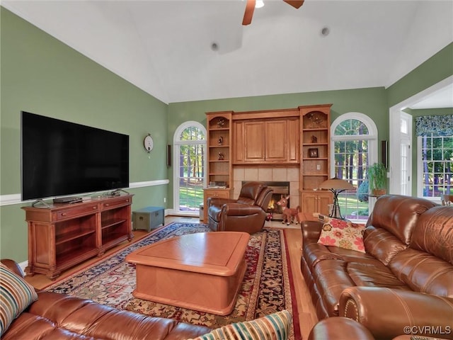 living room with ceiling fan, hardwood / wood-style floors, vaulted ceiling, and a fireplace