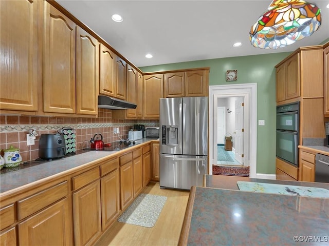 kitchen with tasteful backsplash, black appliances, pendant lighting, and light hardwood / wood-style flooring