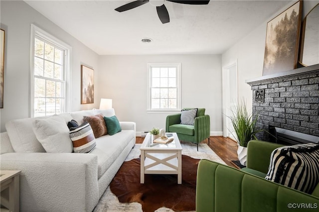 living room with baseboard heating, ceiling fan, hardwood / wood-style flooring, and a fireplace