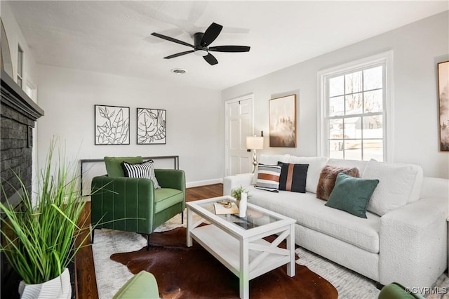 living room featuring ceiling fan, a fireplace, and hardwood / wood-style flooring