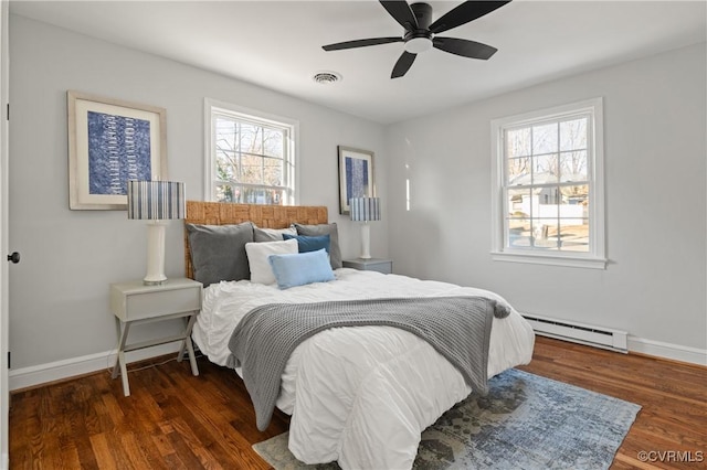 bedroom featuring ceiling fan, baseboard heating, multiple windows, and dark hardwood / wood-style floors