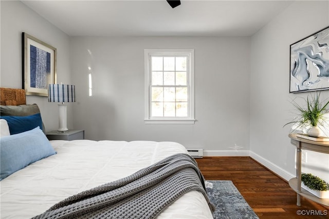 bedroom with a baseboard heating unit and dark hardwood / wood-style floors