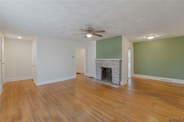 unfurnished living room with a brick fireplace, a textured ceiling, ceiling fan, and light hardwood / wood-style floors