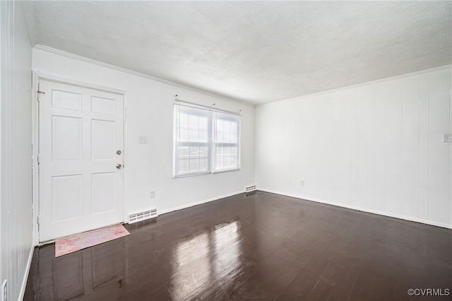 empty room with dark hardwood / wood-style flooring and a textured ceiling