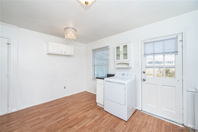 laundry area featuring washer / dryer, light hardwood / wood-style flooring, cabinets, and plenty of natural light