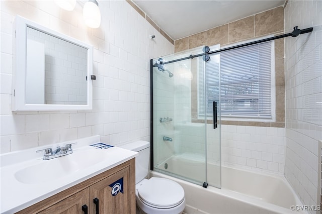 full bathroom featuring vanity, toilet, combined bath / shower with glass door, and tile walls