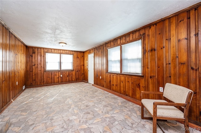 unfurnished room with wooden walls and a textured ceiling