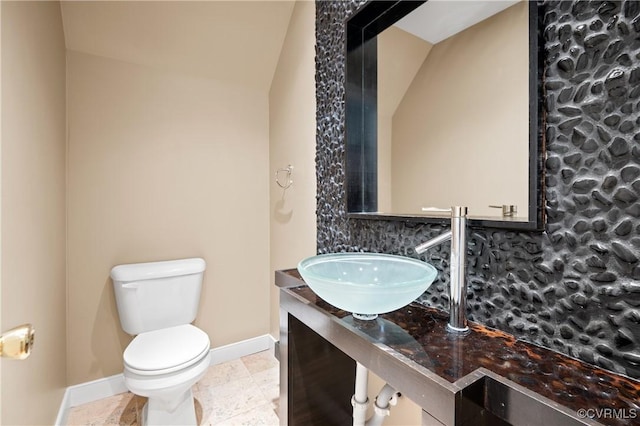 bathroom featuring sink, toilet, and lofted ceiling