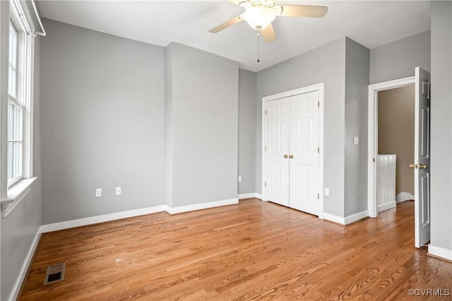 unfurnished bedroom with light wood-type flooring, ceiling fan, and a closet