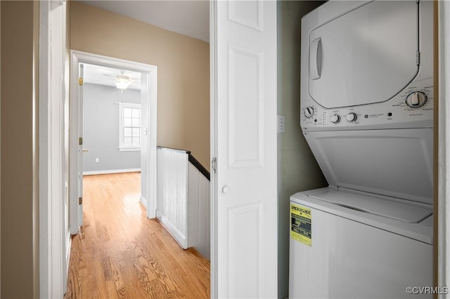 laundry area with light wood-type flooring, stacked washer and dryer, and ceiling fan