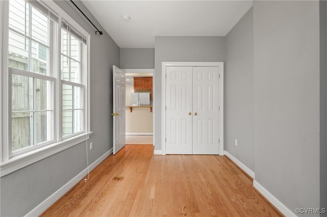 unfurnished bedroom with a closet, light hardwood / wood-style flooring, and stainless steel fridge