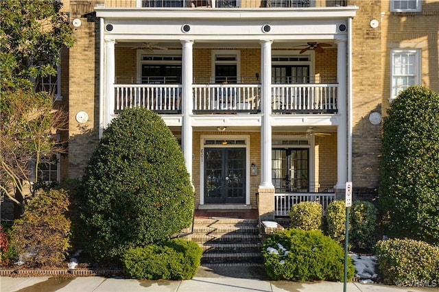 view of front of property featuring french doors, covered porch, ceiling fan, and a balcony