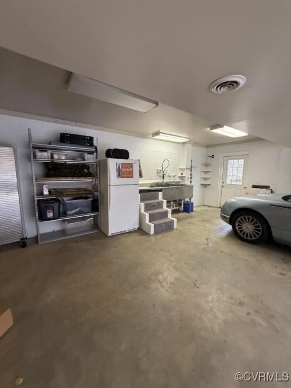 garage featuring visible vents and freestanding refrigerator