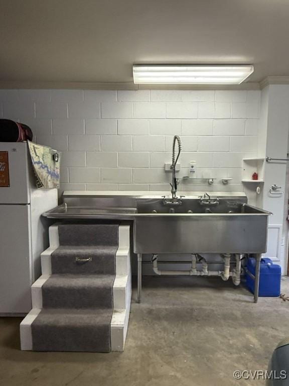 kitchen featuring ornamental molding, freestanding refrigerator, and unfinished concrete floors