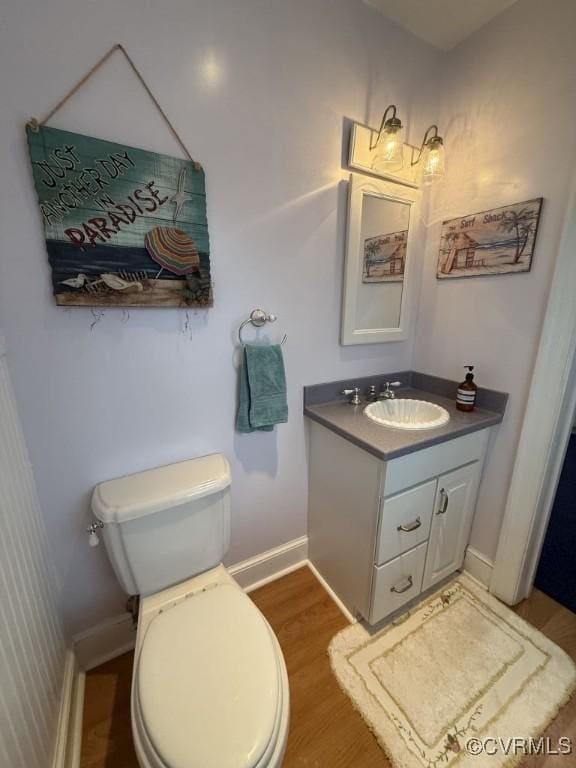 bathroom featuring baseboards, vanity, toilet, and wood finished floors