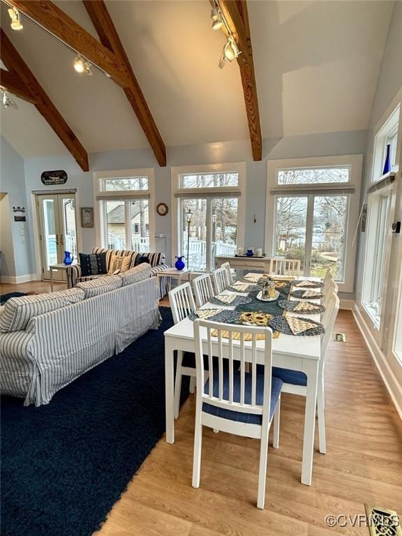 dining space featuring high vaulted ceiling, french doors, light wood-style flooring, and beam ceiling