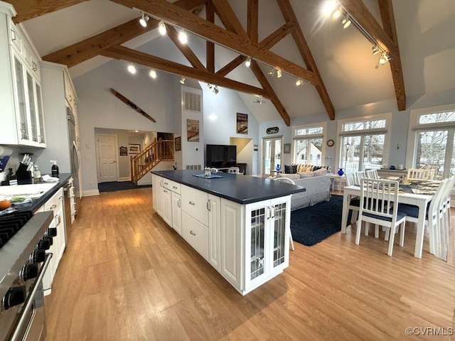 kitchen featuring light wood-style flooring, white cabinetry, high end stainless steel range oven, a center island, and dark countertops