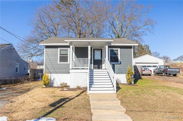 bungalow-style house with a porch, an outbuilding, a front lawn, and a garage