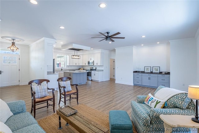 living room featuring ornamental molding, ceiling fan, and light hardwood / wood-style flooring