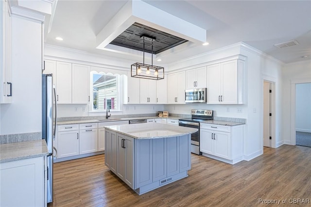 kitchen with stainless steel appliances, sink, white cabinets, decorative light fixtures, and a kitchen island