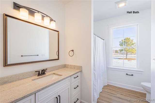 bathroom featuring a healthy amount of sunlight, toilet, vanity, and hardwood / wood-style flooring