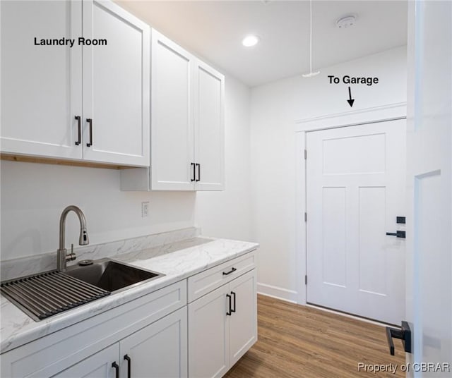 kitchen featuring sink, white cabinets, light hardwood / wood-style flooring, and light stone countertops