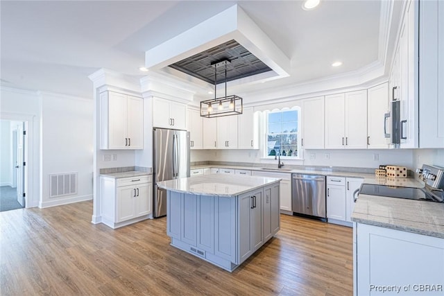 kitchen featuring pendant lighting, a center island, stainless steel appliances, white cabinetry, and sink