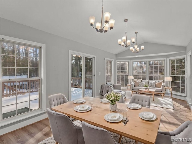 dining area with a chandelier, lofted ceiling, and light hardwood / wood-style flooring