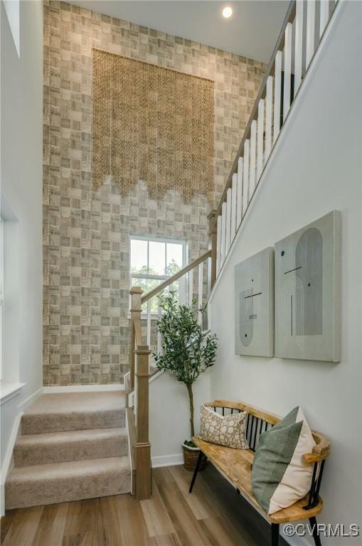 stairs featuring a towering ceiling and hardwood / wood-style floors