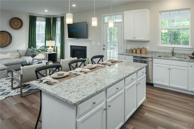 kitchen with white cabinets, dishwasher, a breakfast bar area, a center island, and sink