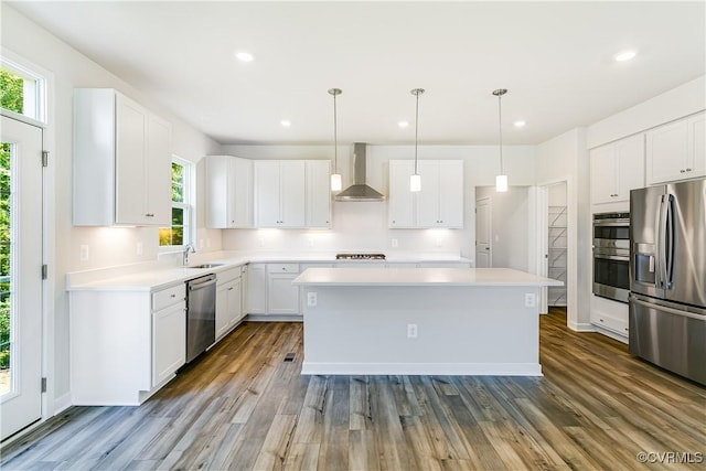 kitchen with a kitchen island, stainless steel appliances, wall chimney exhaust hood, and white cabinets