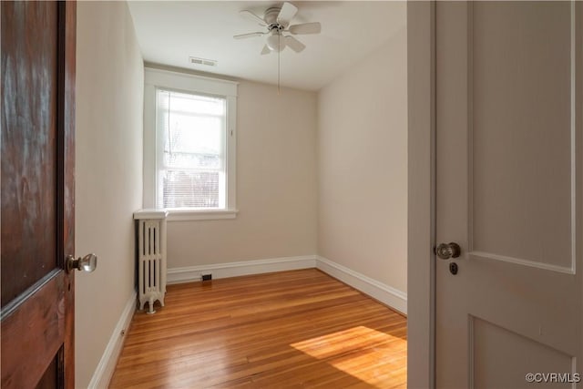 spare room featuring light hardwood / wood-style floors, ceiling fan, and radiator