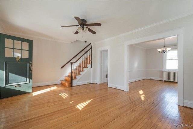 unfurnished living room with radiator, ceiling fan with notable chandelier, ornamental molding, and hardwood / wood-style flooring